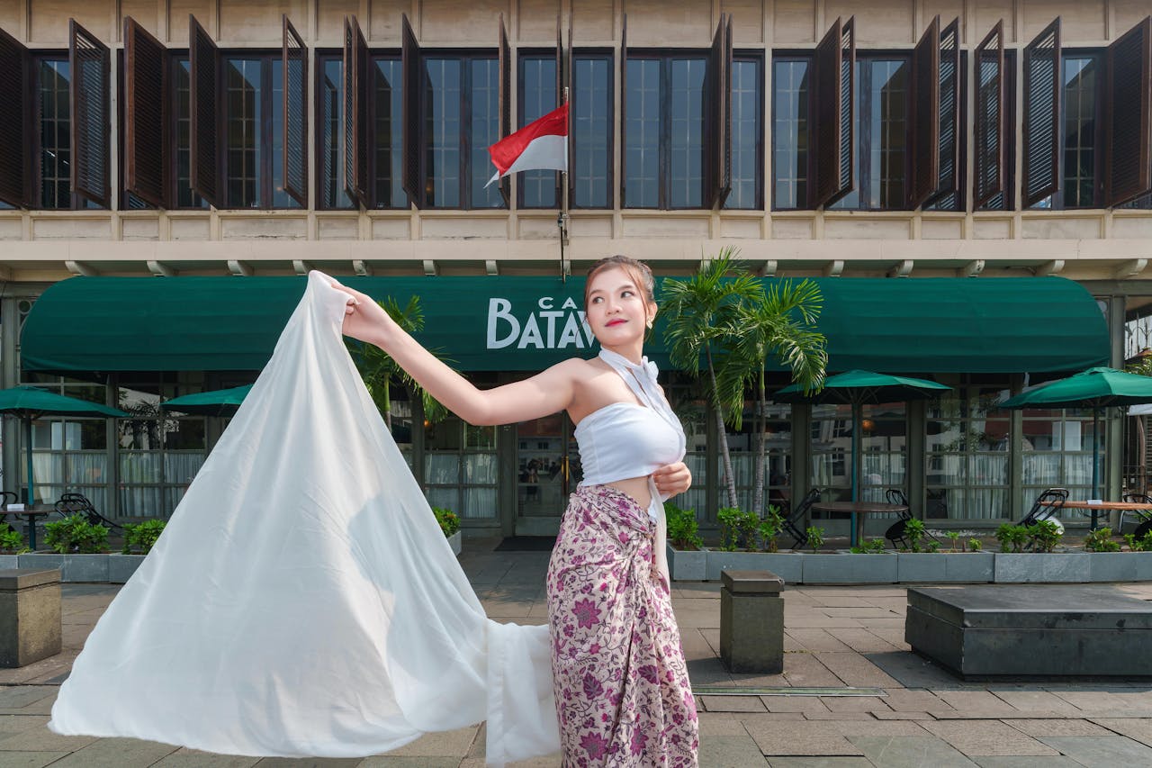 Crafting Captivating Headlines: Your awesome post title goes here Elegant woman poses in traditional attire outside Cafe Batavia, Jakarta.