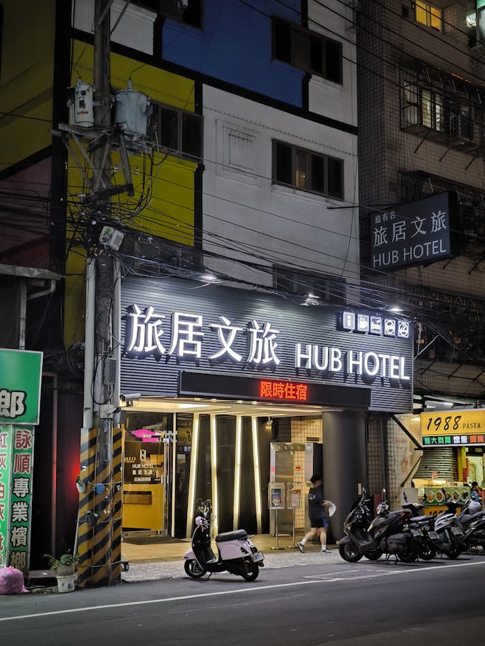 Illuminated exterior of Hub Hotel on a bustling city street at night.