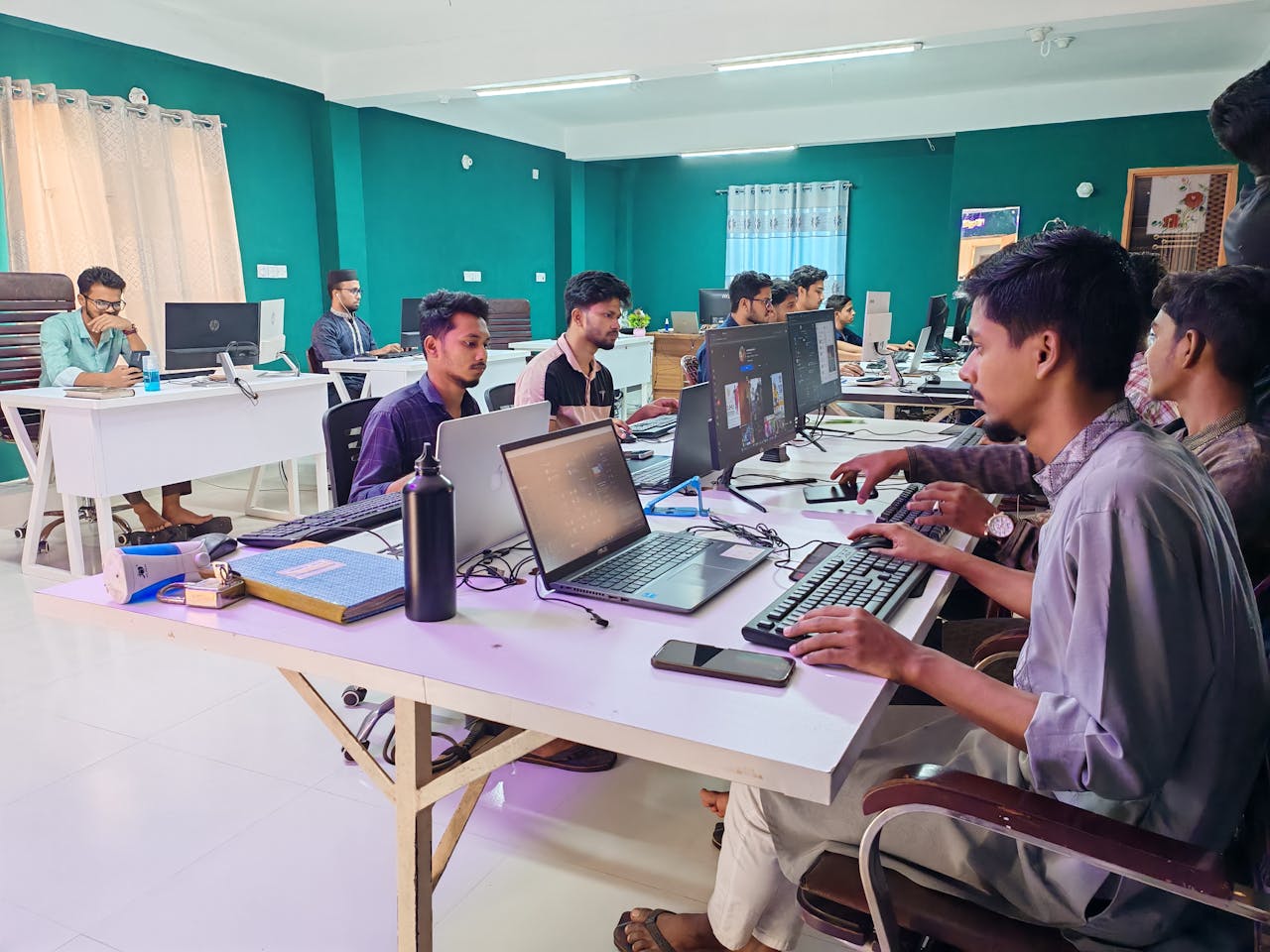 Young professionals working in a bright, modern office environment on computers, fostering collaboration and productivity.