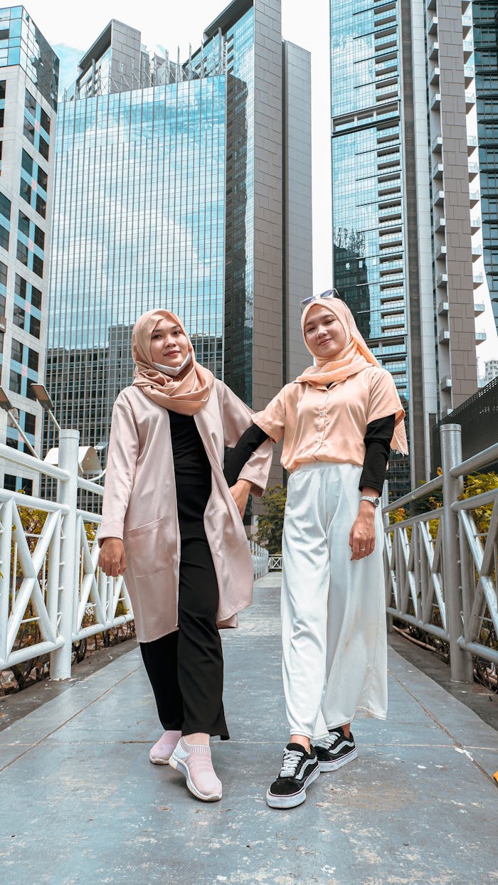Two women wearing hijabs embracing city style in a vibrant urban setting.